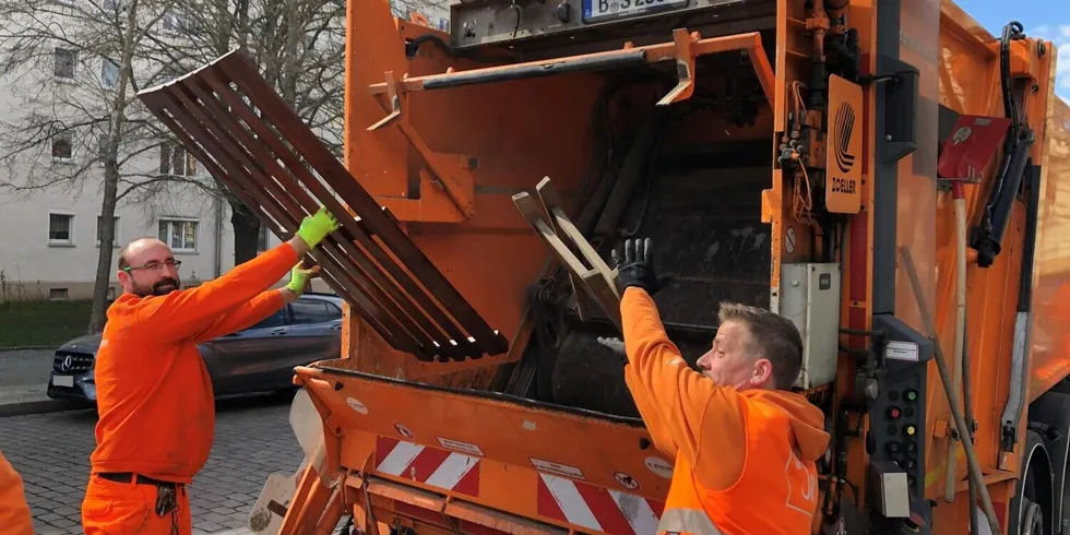 Zwei Männer heben Sperrmüll in die Schüttung eines Müllfahrzeugs.