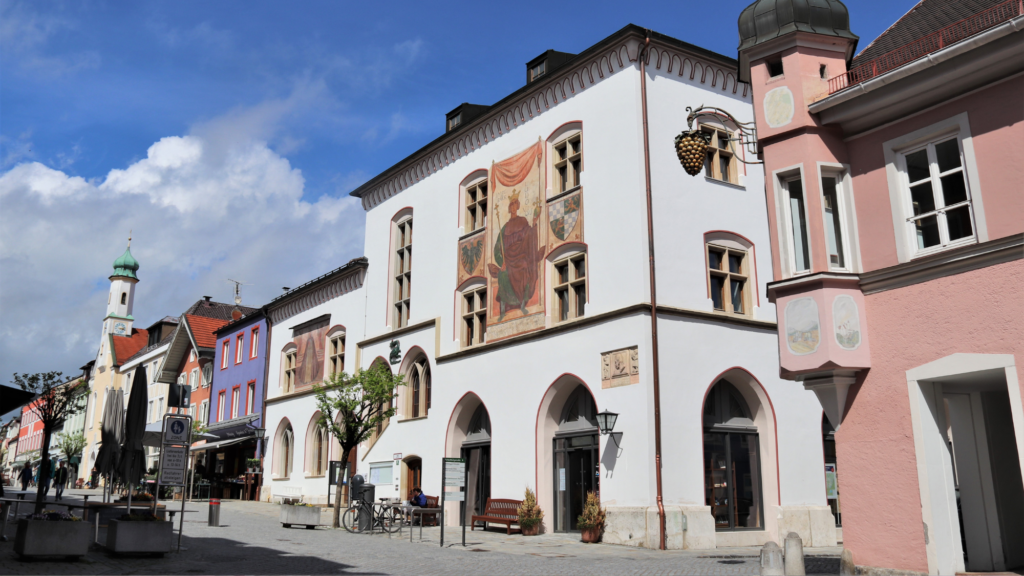 Außenansicht Murnauer Rathaus. Das Gebäude ist ein historisches Rathaus mit Arkaden, verzierter Fassade und einem Wandgemälde an der Fassade.