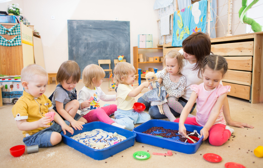 Eine Gruppe von Kleinkindern spielt mit der Erzieherin.