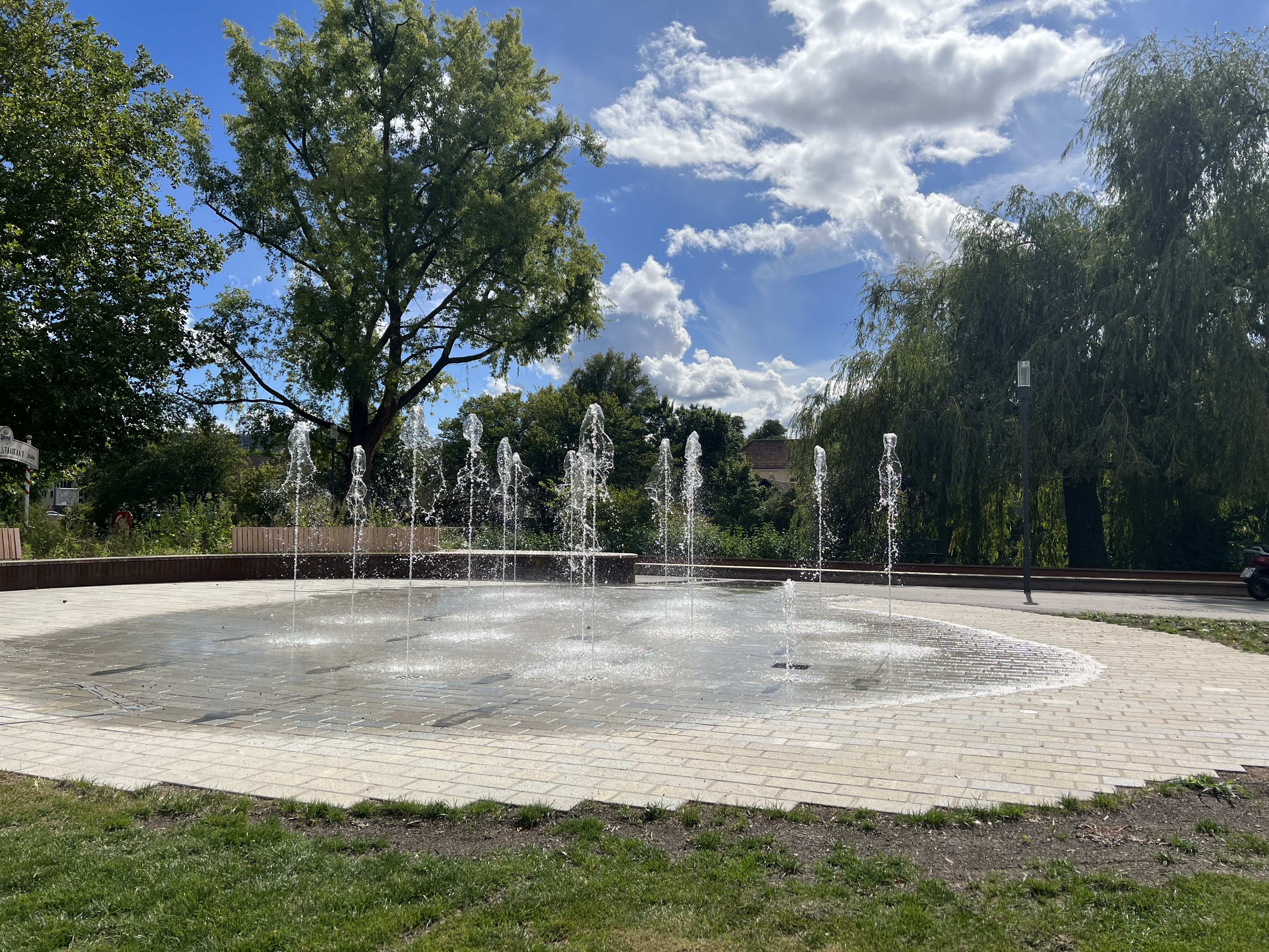 Ein gepflastertes rundes Feld. Wasserfontänen sprudeln in die Höhe.