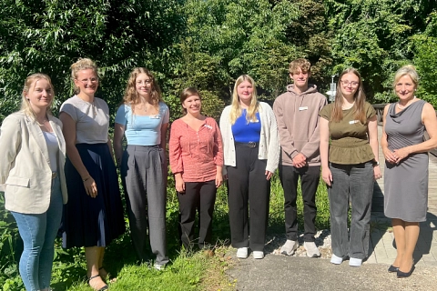 Acht Personen stehen nebeneinander in einer Reihe vor einer grünen Hecke. Landrätin (steht an der rechten Seite)  begrüßt fünf neue Auszubildende und Studierende © Landkreis Lüchow-Dannenberg