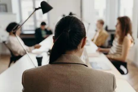 Mehrere Personen sitzen an einem langgestreckten Konferenztisch