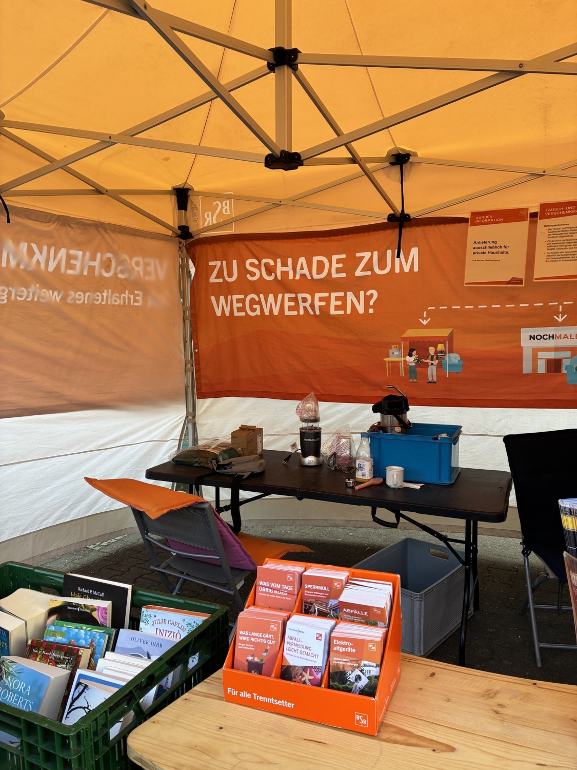 In einem Standzelt sind Tische mit Büchern und Broschüren.