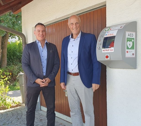 Herr Thomaier VR Bank und Erster Bürgermeister Klaus Kögel neben gespendetem Defi der VR Bank.