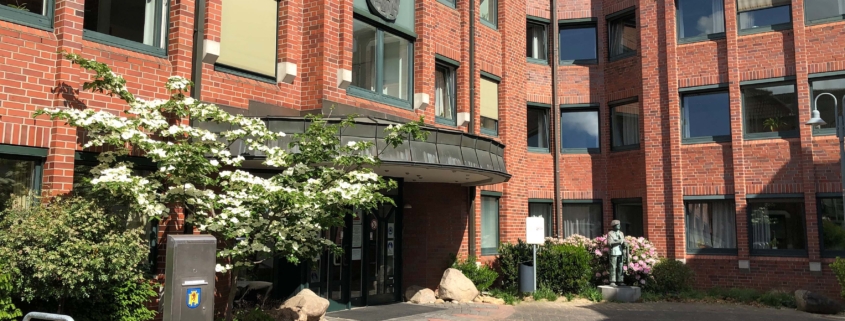 Eingangsbereich Rathaus mit rotem Backstein, große Fenster und Baum vor Eingang