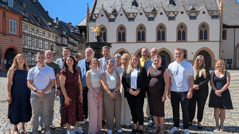 Das Bild zeigt die Genannten auf dem Marktplatz vor dem Marktbrunnen und dem Rathaus.