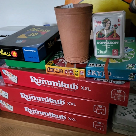 Auf dem Foto sind unterschiedliche Spiele aufeinandergestapelt zu sehen - Phase 10, Doppelkopf, Skipbo, Skyjo, Rummikub XXL. © Richard Henrichs