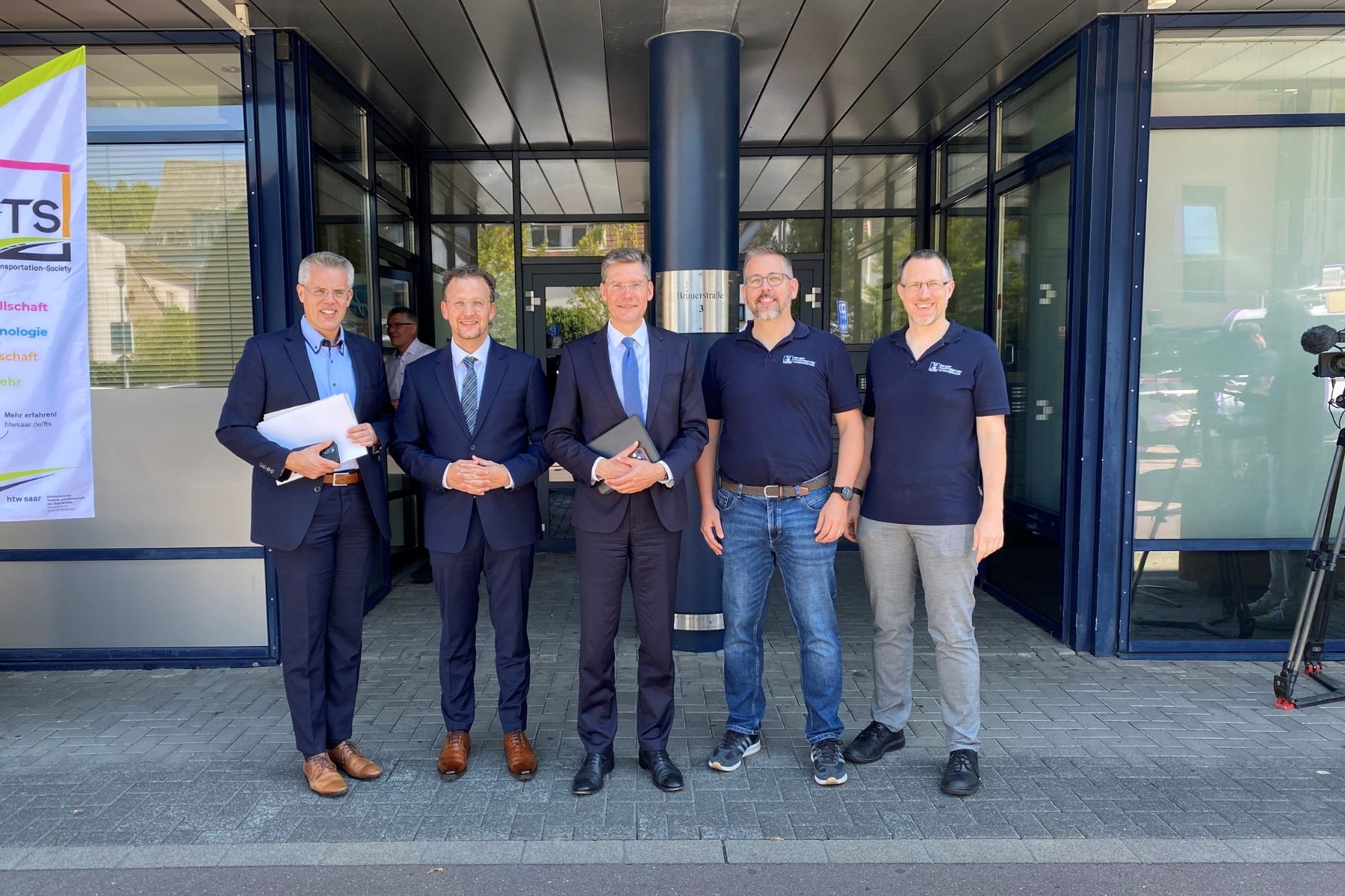 Gruppenfoto mit fünf Herren, sie schauen freundlich in die Kamera, zwei halten Unterlagen in den Händen