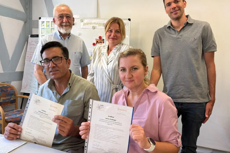 zwei Personen sitzen und drei Personen stehen dahinter