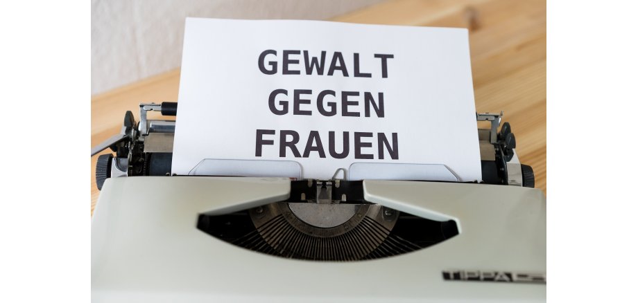 Auf dem Bild ist ein Blatt in einer Schreibmaschine zu sehen, auf dem "Gewalt gegen Frauen" steht