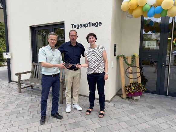 Auf dem Foto sind zwei Männer und eine Frau zu sehen, die einen großen Schlüssel in den Händen halten.