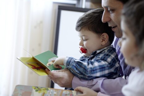 Ein Vater schaut sich mit seinen kleinen Kindern ein Bilderbuch an