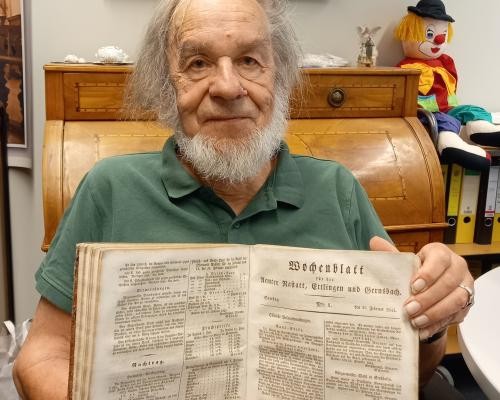 Johannes Werner hält historische Bände des Rastatter Wochenblatts in den Händen. Foto: Martin Walter/Kreisarchiv
