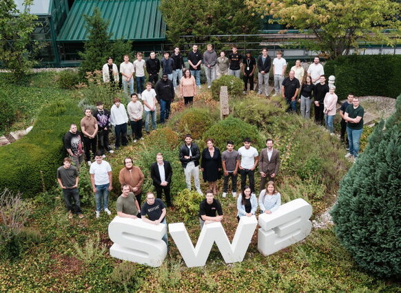 Das Drohnenfoto zeigt eine Gruppe von fast 40 jungen Menschen, die um die Buchstaben SWB herum in einem Garten stehen