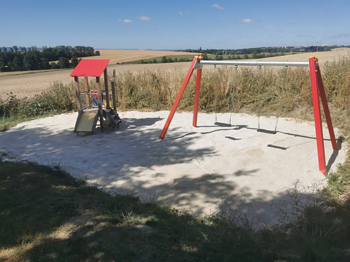 Bild: Eine Rutsche und zwei Schaukeln auf einem kleinen Spielplatz mit Sanduntergrund