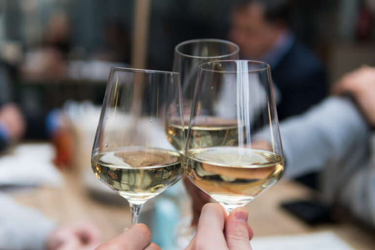 Weingläser mit Weißwein stoßen an