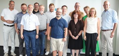 das foto zeigt Die Teilnehmenden des Info-Meetings (v.l.n.r.): SÜW-Landrat Dietmar Seefeldt, Simon Wingerter (Bürgermeister der Verbandsgemeinde Offenbach an der Queich), Marco Stoll Vertragsmanager Bus beim Zweckverband Schienenpersonennahverkehr Rheinland-Pfalz Süd (ZÖPNV Süd), Martin Hammer (Ortsbürgermeister Essingen), Hannes Kirsch (Ortsbürgermeister Lustadt), Bernward Heinemann (Bereichsleiter Süd-West bei der STE Management GmbH und externer Experte für Bahnprojektplanung), Timo Freund (Beigeordneter der Ortsgemeinde Lingenfeld), Michael Heilmann, ZÖPNV Süd-Verbandsdirektor, Elke Thomas (Ortsbürgermeisterin Bornheim), dahinter Marcus Schaile (Bürgermeister der Stadt Germersheim), Susanne Grabau (Ortsbürgermeisterin Westheim), Susanne Lechner (Ortsbürgermeisterin Zeiskam), Martin Brandl, Landrat für den Kreis Germersheim.