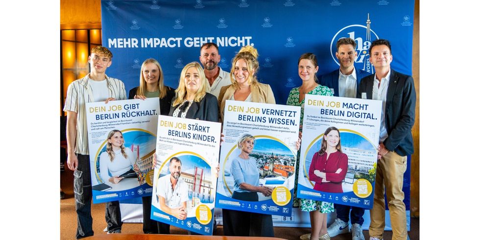 Vorstellung Arbeitgebermarke "ChaWi WORKS" am Mittwoch, 26. August 2026. Bezirksbürgermeisterin Kirstin Bauch mit Mitarbeitenden und Markenbotschafter:innen vor einem großen blauen Banner mit der Aufschrift (weiß) "Mehr Impact geht nicht". Vor sich präsentieren alle Beteiligten die vier Kampagnen-Poster, welche die Markenbotschafter:innen zeigen mit verschiedenen Slogans: (v.l.n.r.) "Dein Job gibt Berlin Rückhalt.", "Dein Jop stärkt Berlins Kinder.", "Dein Job vernetzt Berlins Wissen.", "Dein Job macht Berlin digital."