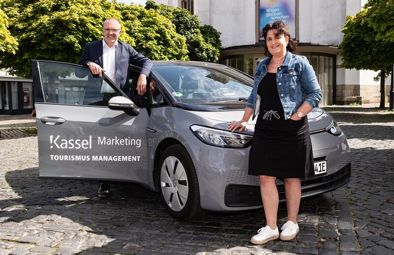 Zwei Menschen vor dem Auto der Kassel Marketing GmbH