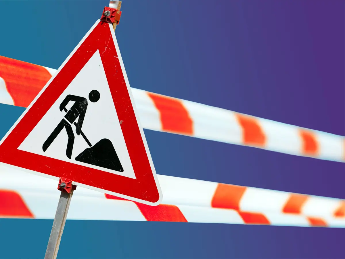 Ein Straßenschild weist auf Bauarbeiten hin, Flatterband auf eine Sperrung.