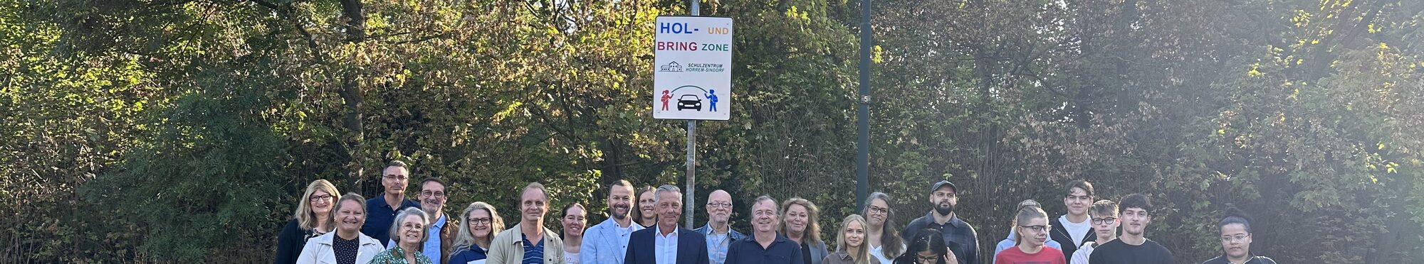 Eine Gruppe von Personen unter dem Schild Hol- und Bring-Zone