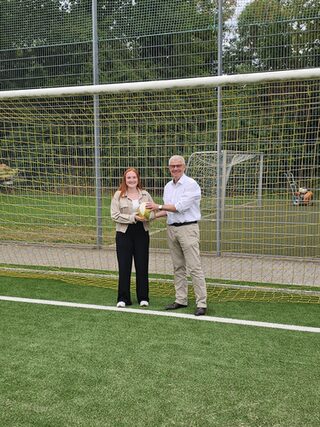 Annika Kluth Sachbearbeiterin Schule und Sport und Bürgermeister Dr. Marc Prokop auf dem Kunstrasen