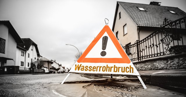 Schild mit Aufschrift "Wasserrohrbruch" steht auf Straße