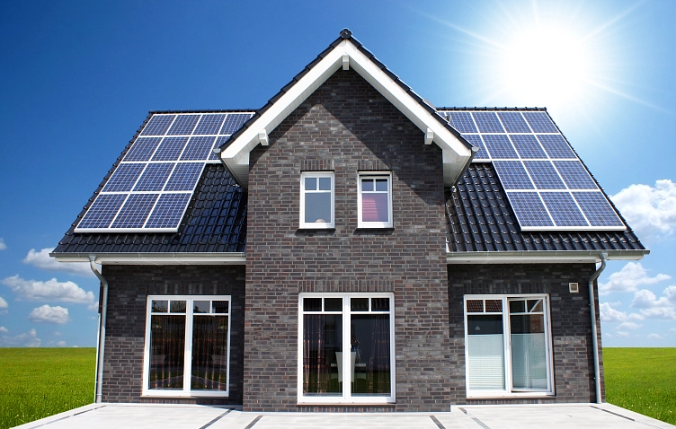 Zweifach-Haus mit Solarpanelen auf dem Dach vor blauem Himmel und grüner Wiese. © Mark Mumm_pixelio.de