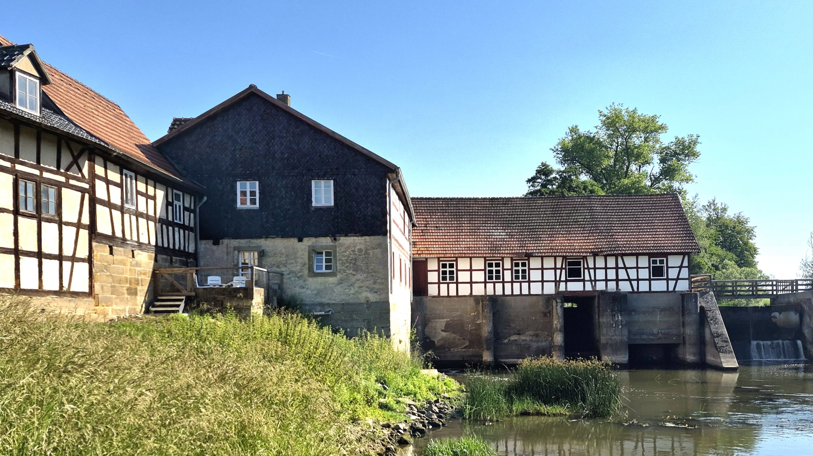 Die Mühle in der Schenkenau, ein historisches Fachwerkgebäude mit einem Bachlauf davor.
